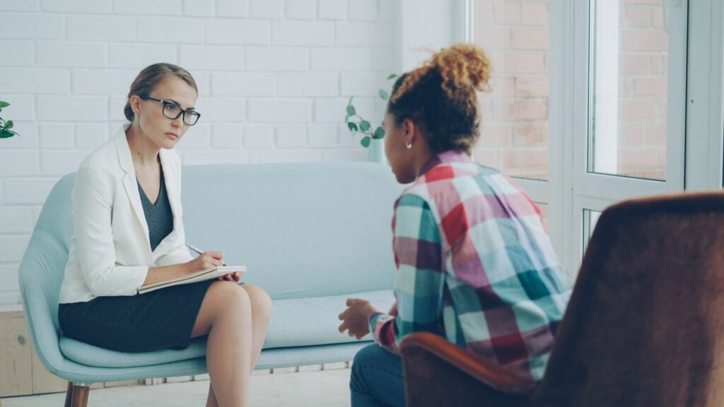 Coach y cliente en conversación cercana, escuchando sin resolver por el otro
