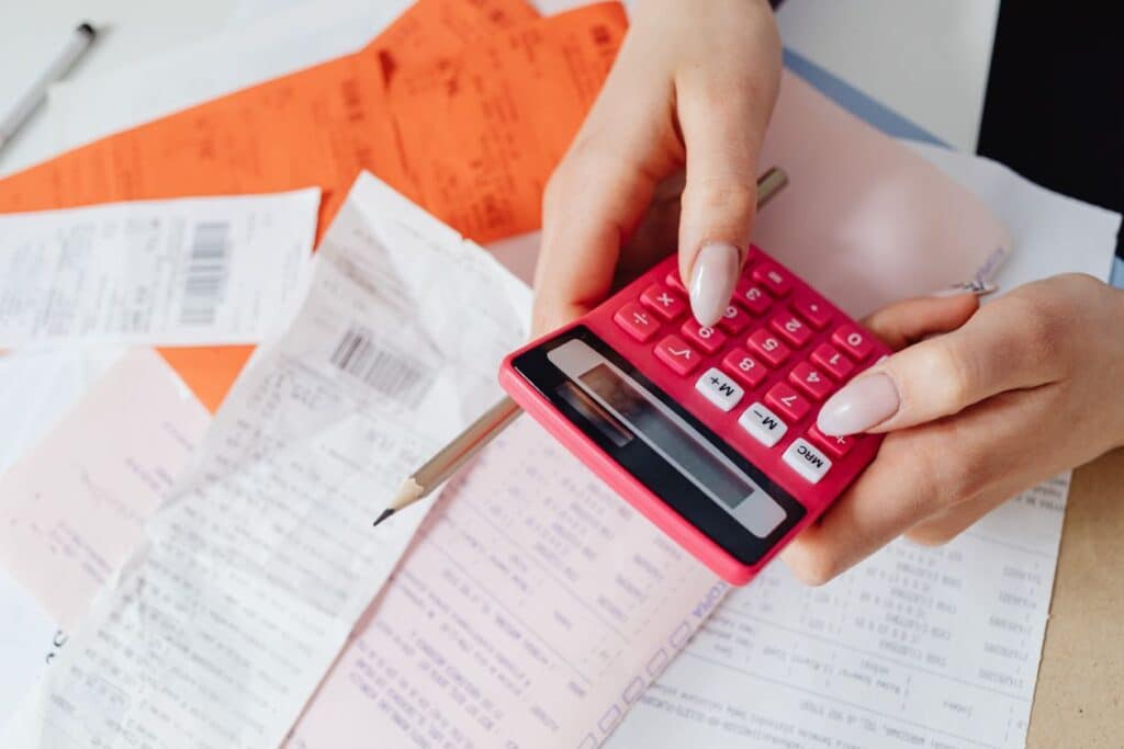 Persona usando calculadora para revisar precios y facturas de su negocio