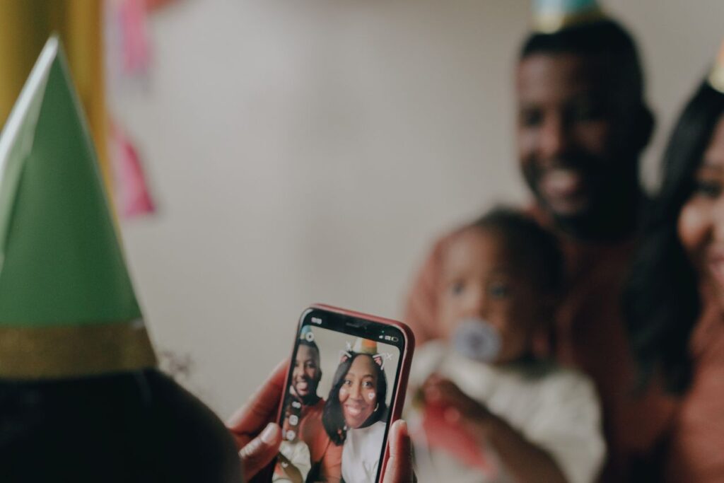 En una fiesta de cumpleaños, alguien mira en el teléfono la foto recién tomada de una pareja sonriendo con gorros de fiesta